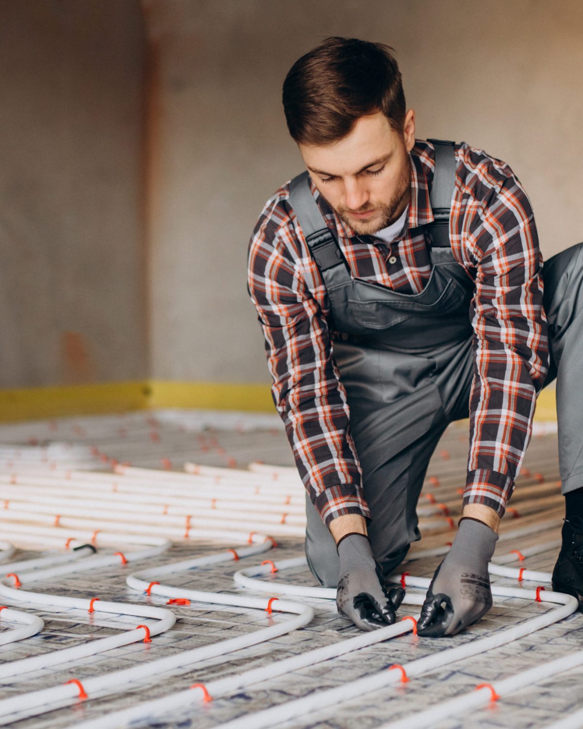 Service man instelling house heating system under the floor